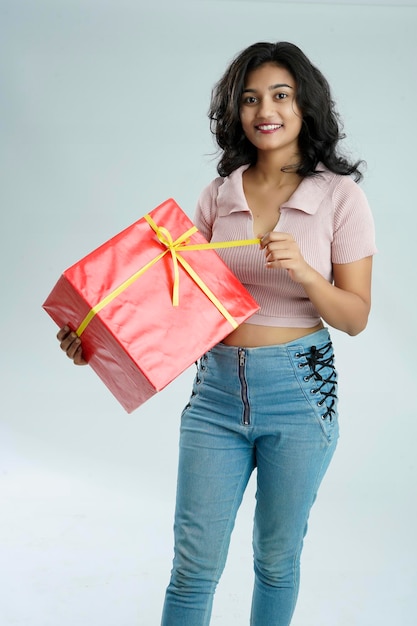 hermosa joven india sosteniendo una pila de cajas de regalos mientras usa una camiseta aislada sobre un fondo blanco