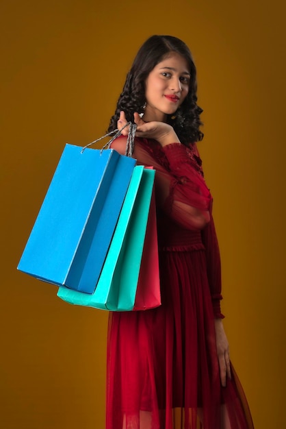 Hermosa joven india sosteniendo y posando con bolsas de compras en un fondo marrón