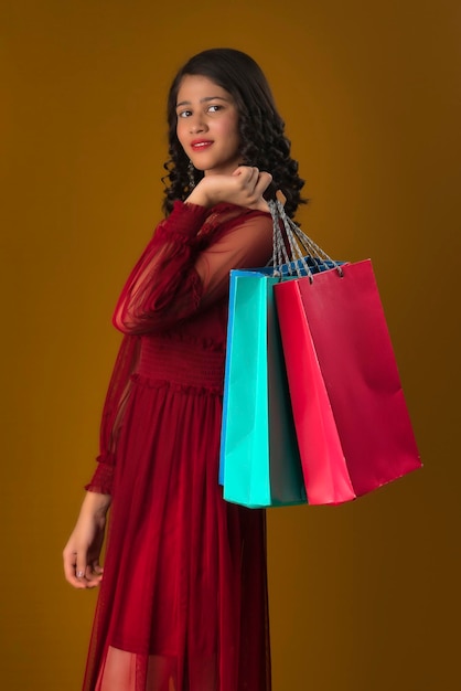 Hermosa joven india sosteniendo y posando con bolsas de compras en un fondo marrón