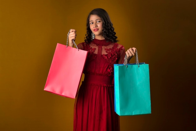 Hermosa joven india sosteniendo y posando con bolsas de compras en un fondo marrón