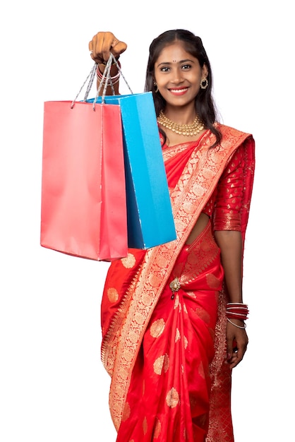 Hermosa joven india sosteniendo y posando con bolsas de compras sobre un fondo blanco.