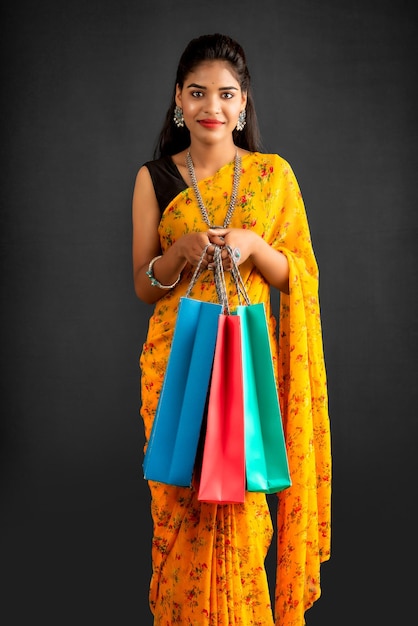 Hermosa joven india sosteniendo y posando con bolsas de compras sobre un fondo gris