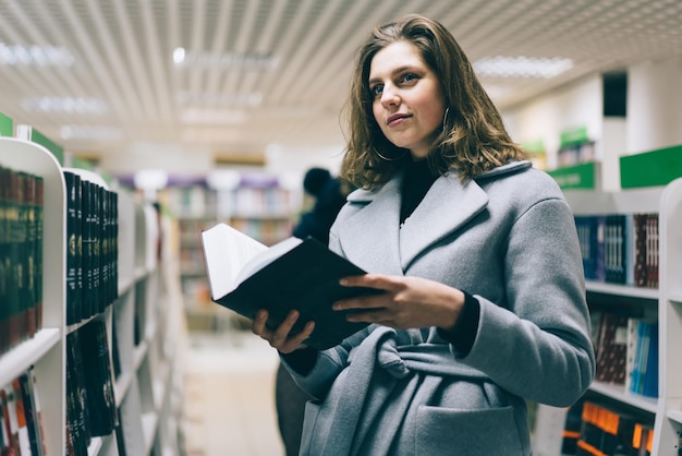 Hermosa joven inteligente leyendo un libro en la librería