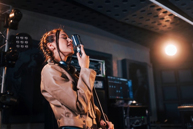 Hermosa joven intérprete femenina canta y ensaya en un estudio de grabación