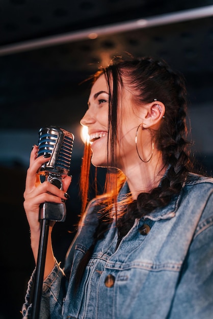 Hermosa joven intérprete femenina canta y ensaya en un estudio de grabación