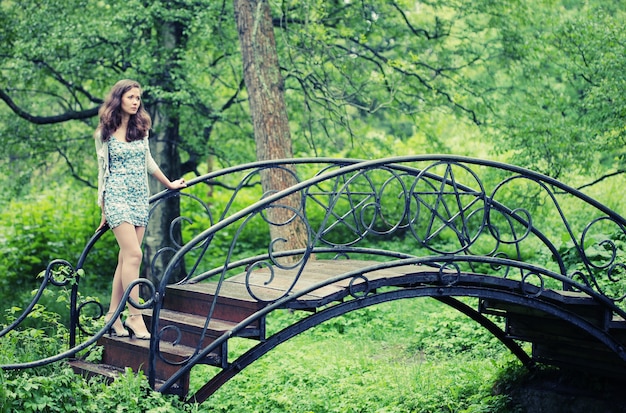 Hermosa joven en jardín en el puente