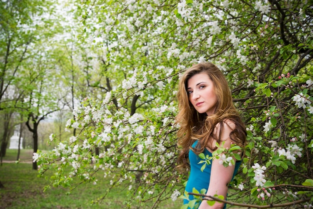 Hermosa joven en jardines florecientes de primavera