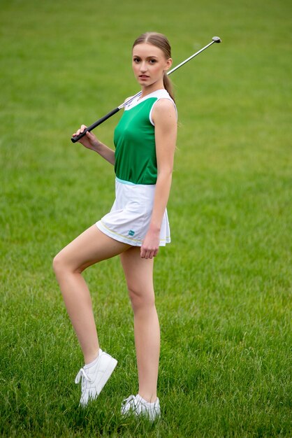 Hermosa joven jugando al golf en la hierba verde