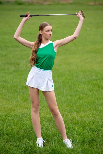 Hermosa joven jugando al golf en la hierba verde