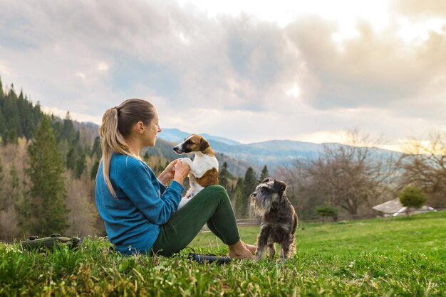 Hermosa joven jugando con perros en la naturaleza en las montañas