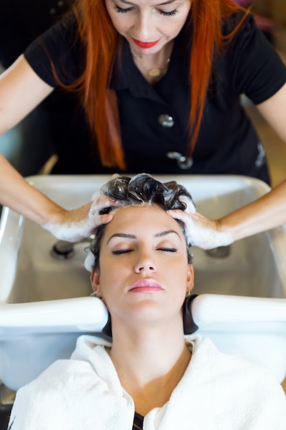 Foto hermosa joven lava el cabello en un salón de belleza.