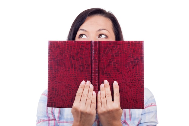 Hermosa joven leyendo un libro y oculta su rostro sobre un fondo blanco.