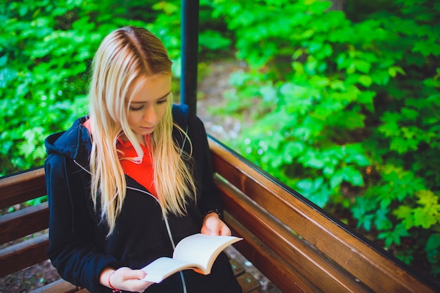 Hermosa joven con libro en bosque otoñal