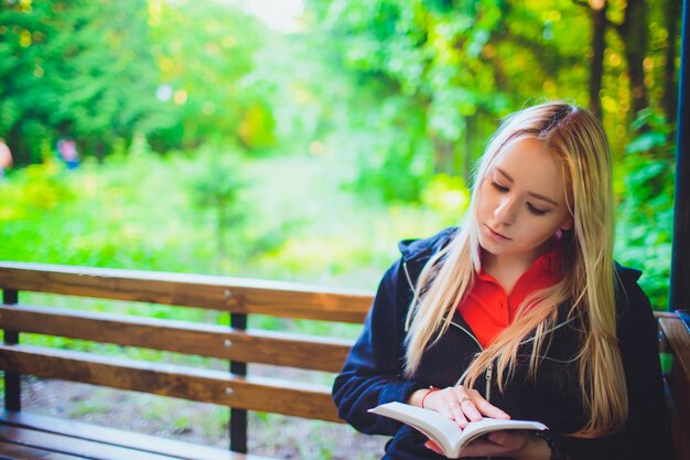 Hermosa joven con libro en bosque otoñal