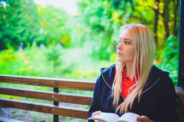 Hermosa joven con libro en bosque otoñal