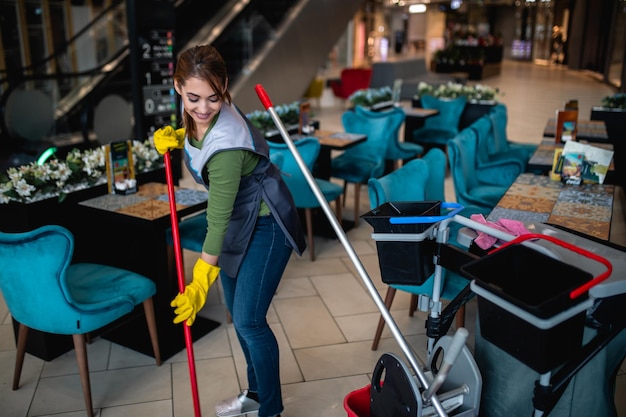 Hermosa joven limpiando en el centro comercial. Concepto de limpieza.