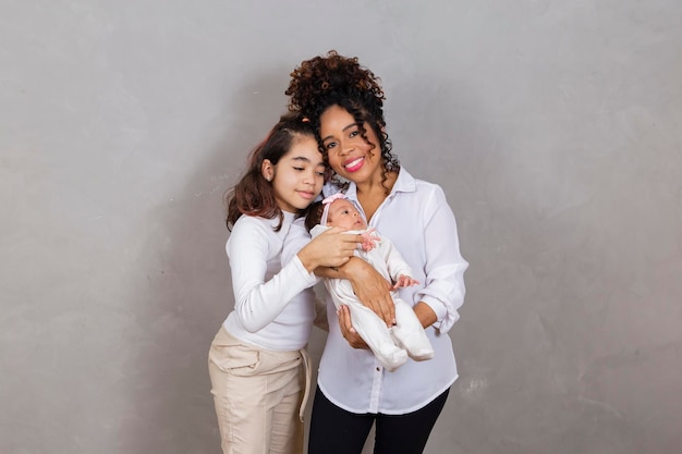 Hermosa joven madre afro con sus hijas sobre fondo gris Madre hija y bebé