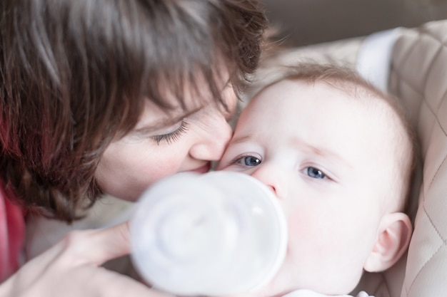 Hermosa joven madre alimentando a su bebé de biberón