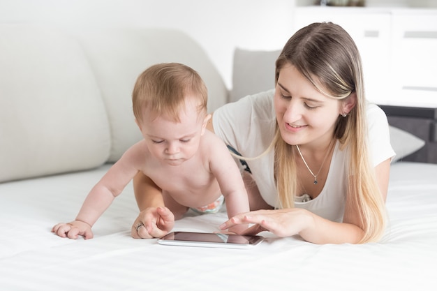 Hermosa joven madre enseñando a su bebé cómo tablet PC