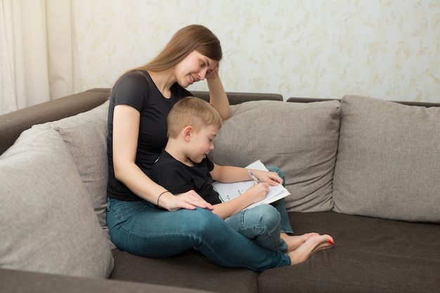 hermosa joven madre de familia e hijo hacen lecciones de tarea