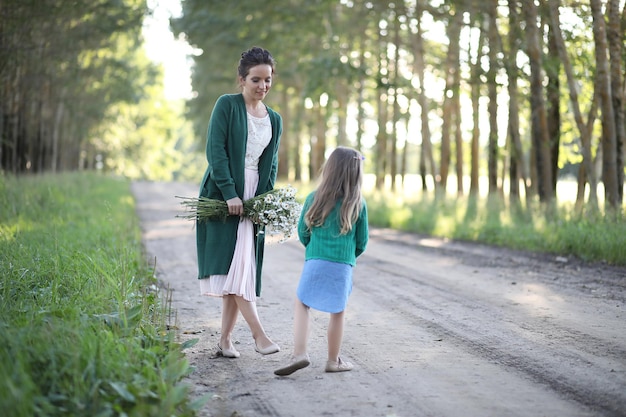 Hermosa joven madre con hija caminando por un camino rural