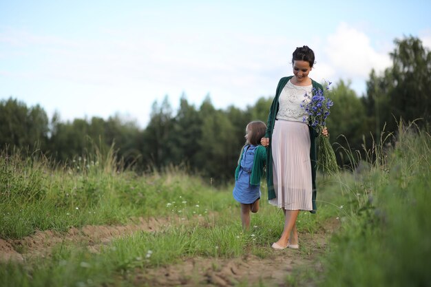 Hermosa joven madre con hija caminando por un camino rural