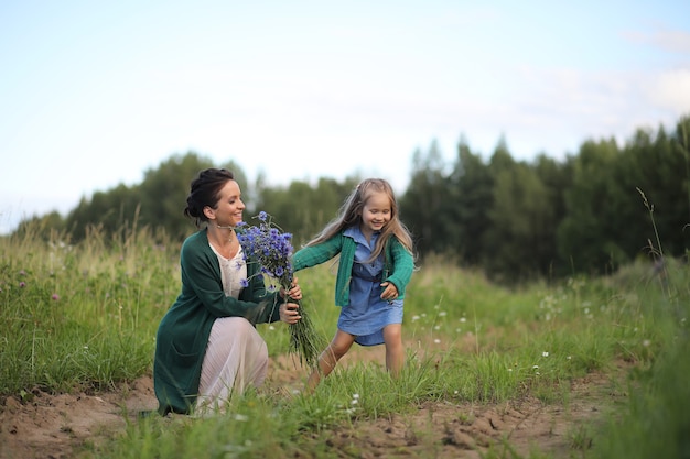 Hermosa joven madre con hija caminando por un camino rural