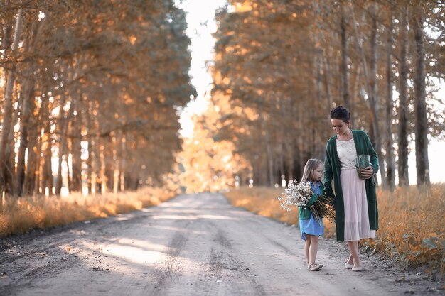 Hermosa joven madre con hija caminando por una carretera