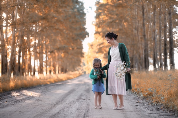 Foto hermosa joven madre con hija caminando por una carretera