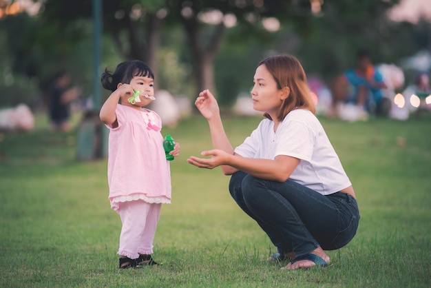 Hermosa joven madre juega con su hija con diversión en el patio de recreoFeliz día de la madreGente de Tailandia