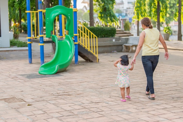 Hermosa joven madre juega con su hija con diversión en el patio de recreoFeliz día de la madreGente de Tailandia