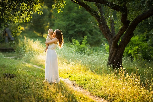 Hermosa joven madre juega con su hijo al aire libre.