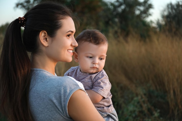 Hermosa joven madre con lindo bebé al aire libre