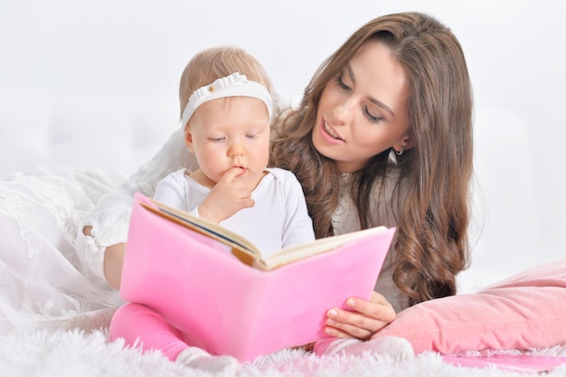 Hermosa joven madre con lindo libro de lectura de hija