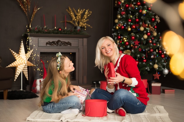 Hermosa joven madre con su hija cerca del árbol de Navidad