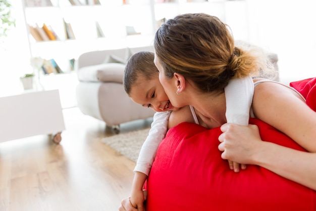 Foto hermosa joven madre y su hijo se divierten en casa.