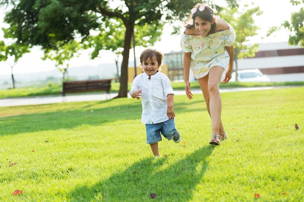 Hermosa joven madre con su hijo se divierten en el parque.