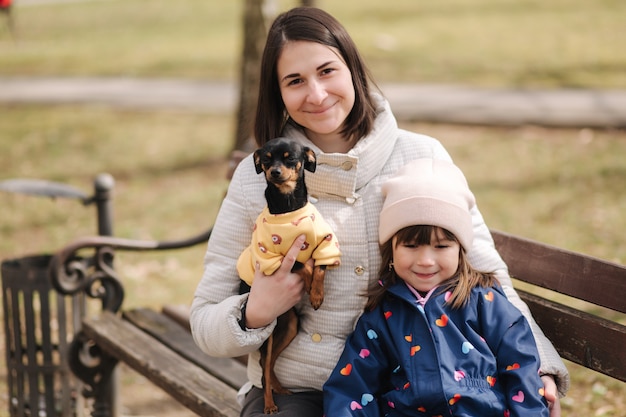 Hermosa joven mamá caminar con hija y perrito familia feliz caminando al aire libre con mascota durante