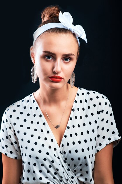 Hermosa joven con maquillaje pin-up y peinado posando en el estudio.