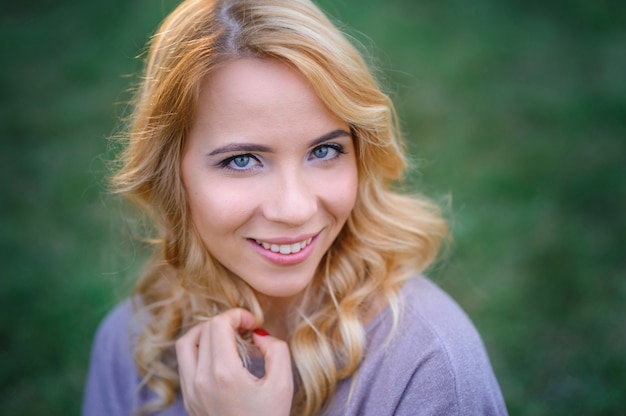 Hermosa joven con maquillaje posando en un parque de verano