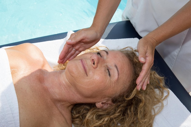 Hermosa joven con masaje facial en el salón de spa