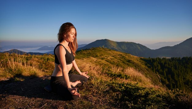 Hermosa joven meditando en las montañas