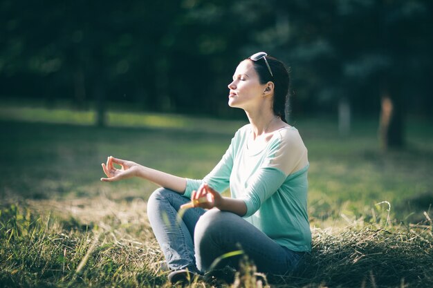 hermosa joven meditando en posición de loto sentado en el césped. foto con espacio de copia