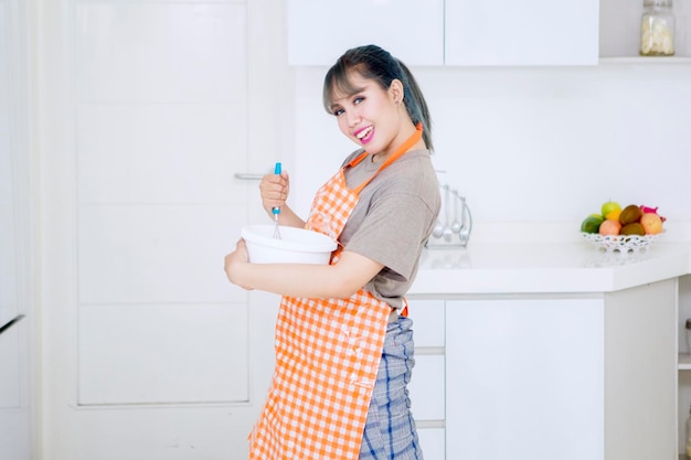 Hermosa joven mezclando masa en la cocina