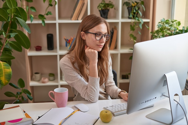 Hermosa joven mirando la pantalla de la computadora en la habitación