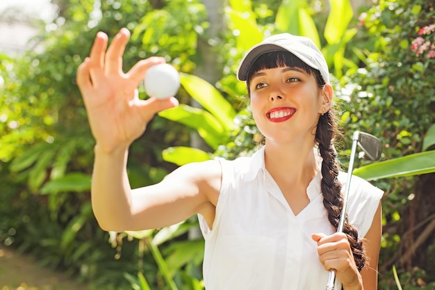 Hermosa joven mirando la pelota de golf