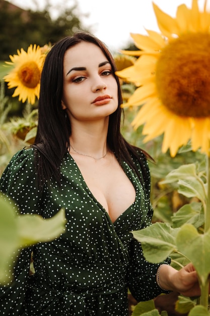 Hermosa joven modelo camina olfatea a través de un ramo amarillo floreciente campo de girasol al aire libre