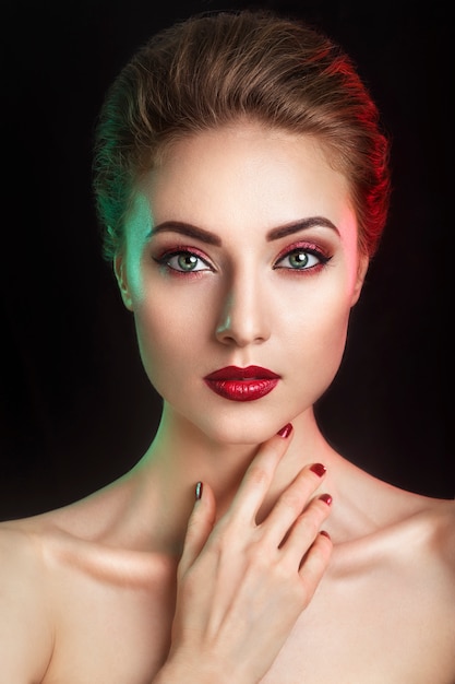 Hermosa joven modelo elegante con labios rojos y maquillaje de noche de color.