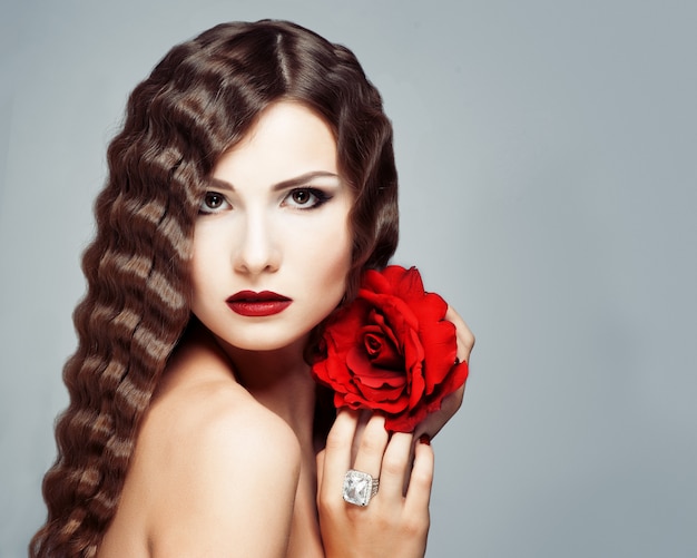 Hermosa joven modelo con labios rojos y rosa roja.