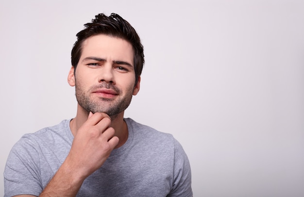 Una hermosa joven modelo masculino toca su barba.